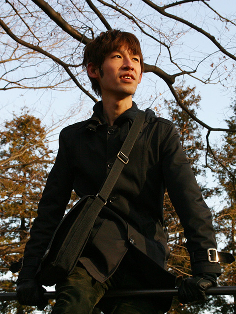 debiru の顔写真。晴れた空の下、黒一色の服装で公園の鉄棒の上に跨って手前側を見ている。